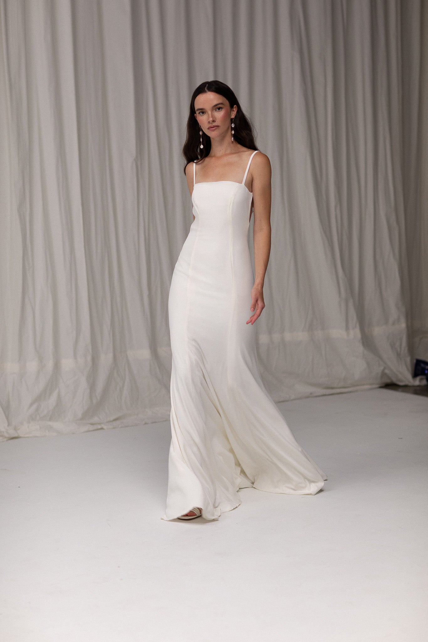 Model wearing an open back crepe gown from TEMPÊTE, featuring a voluminous skirt and square neckline for a sophisticated bridal look.