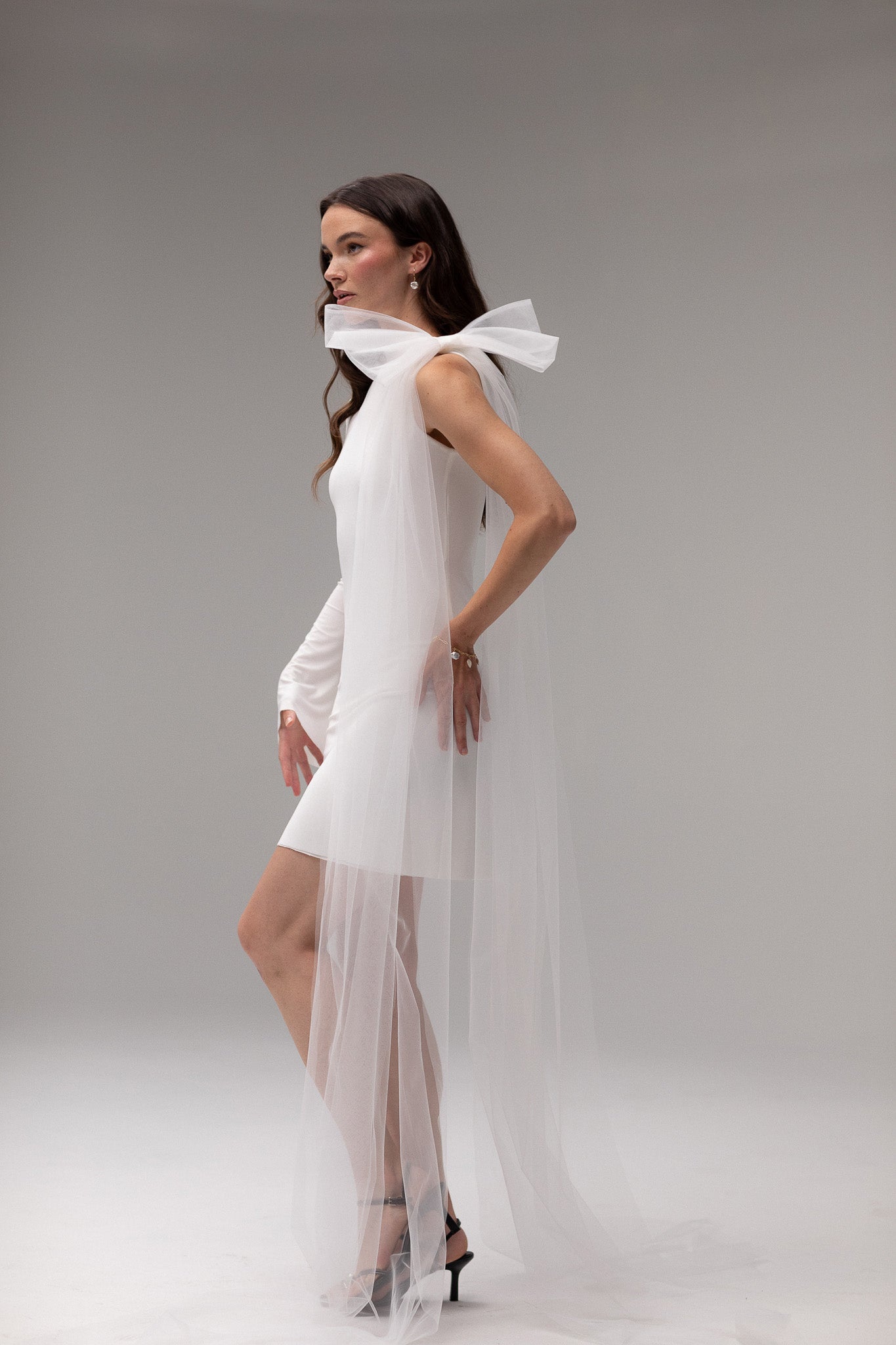 Model wearing a one-sleeve knit dress from the J'OSE Collection by TEMPÊTE, featuring a sleek silhouette and modern, asymmetric design for a bold bridal look.