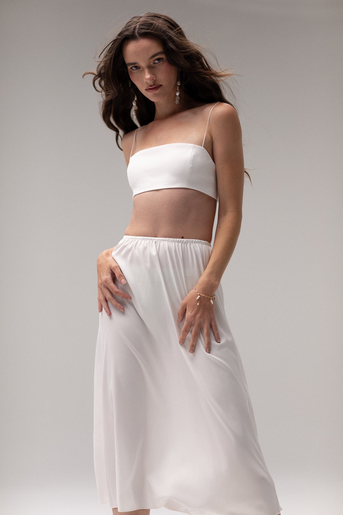 Model wearing a midi satin slip skirt by TEMPÊTE, featuring a smooth satin finish and elegant mid-length.