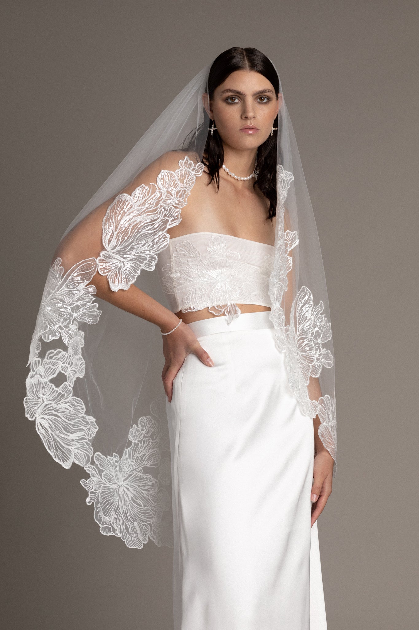 This veil showcases a breathtaking French lace trim that gracefully frames its edges, shimmering delicately in the sunlight to accentuate your bridal look.
