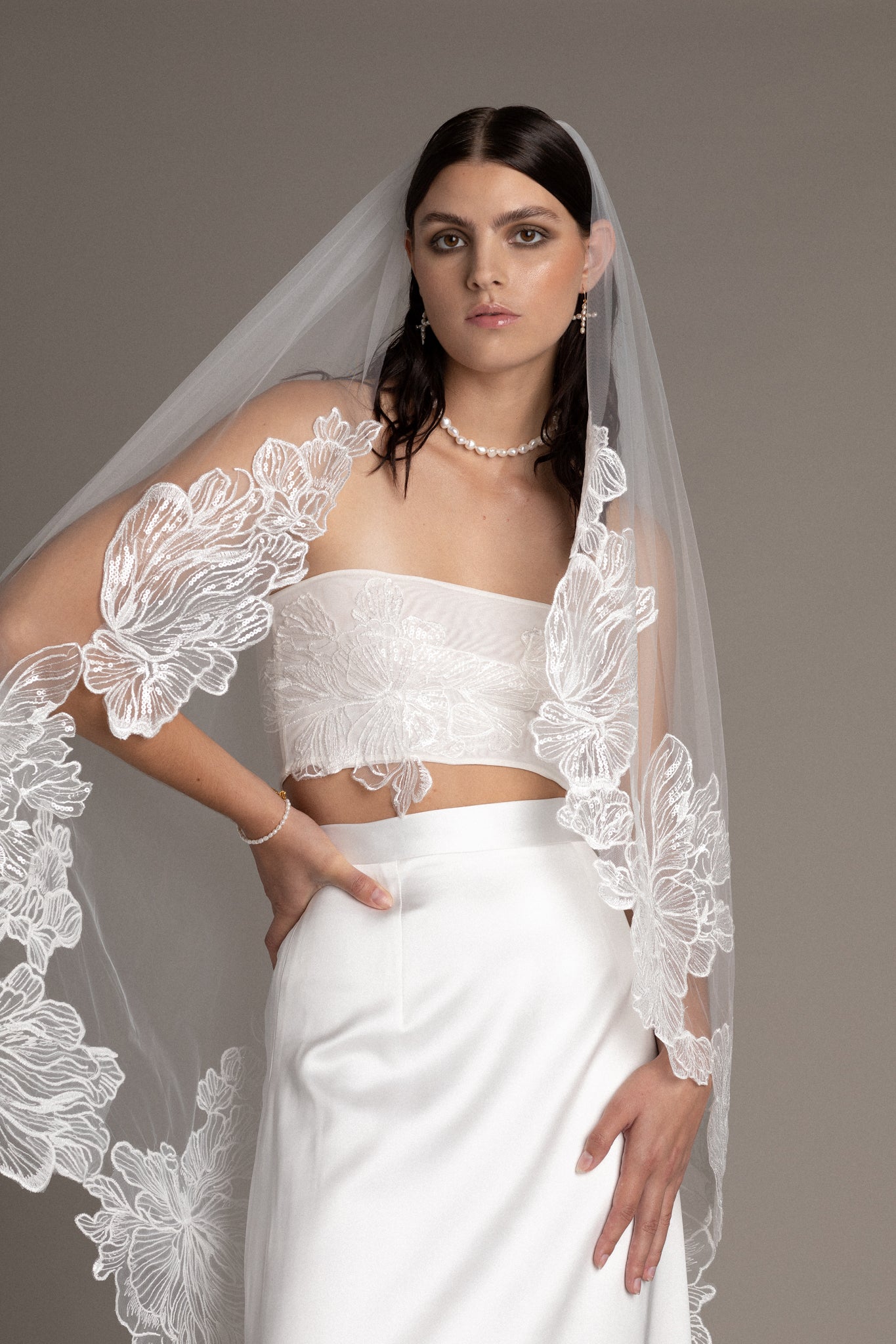 This veil showcases a breathtaking French lace trim that gracefully frames its edges, shimmering delicately in the sunlight to accentuate your bridal look.
