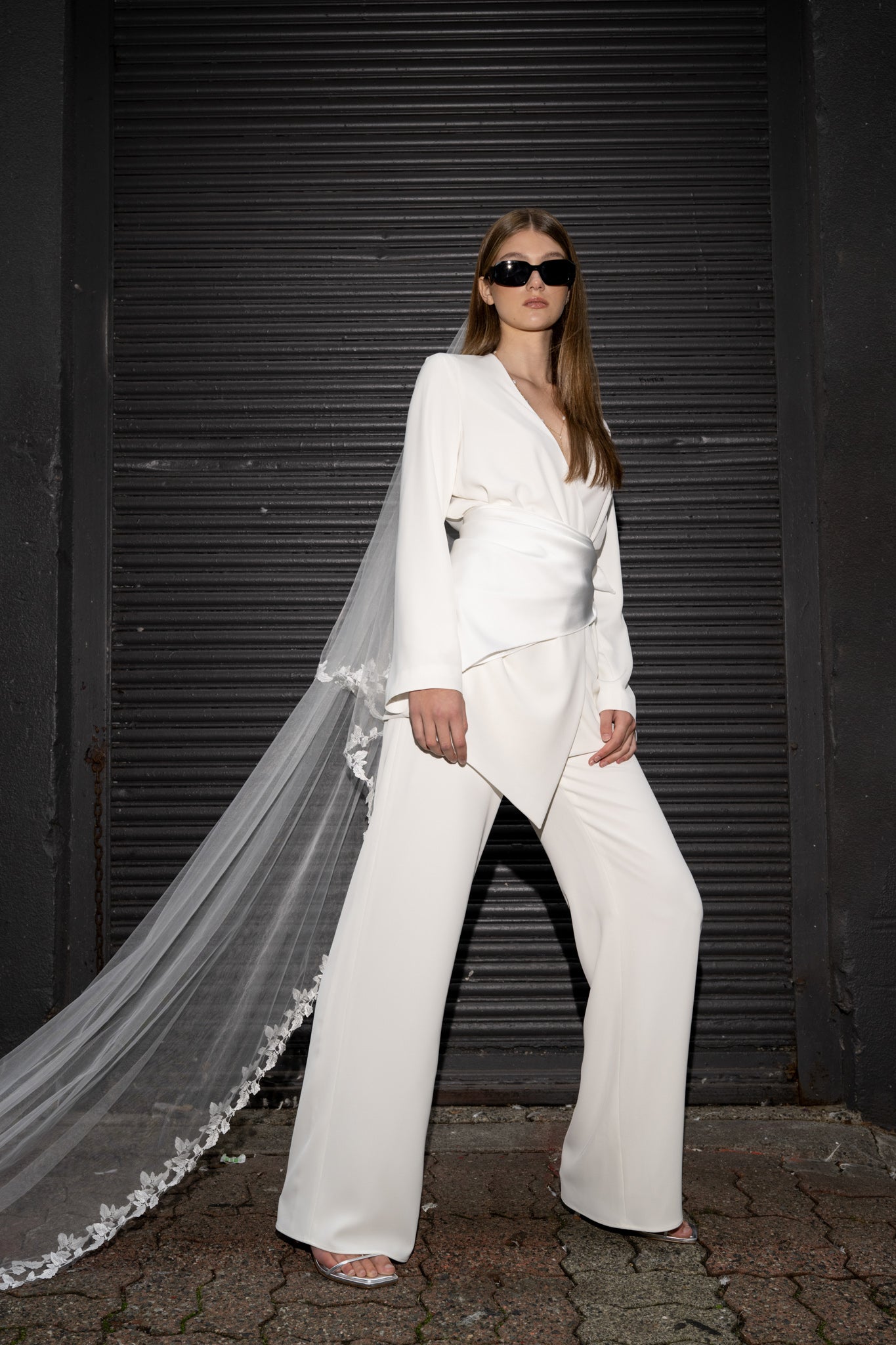 Bride is wearing a pant suit with floral cathedral tulle veil