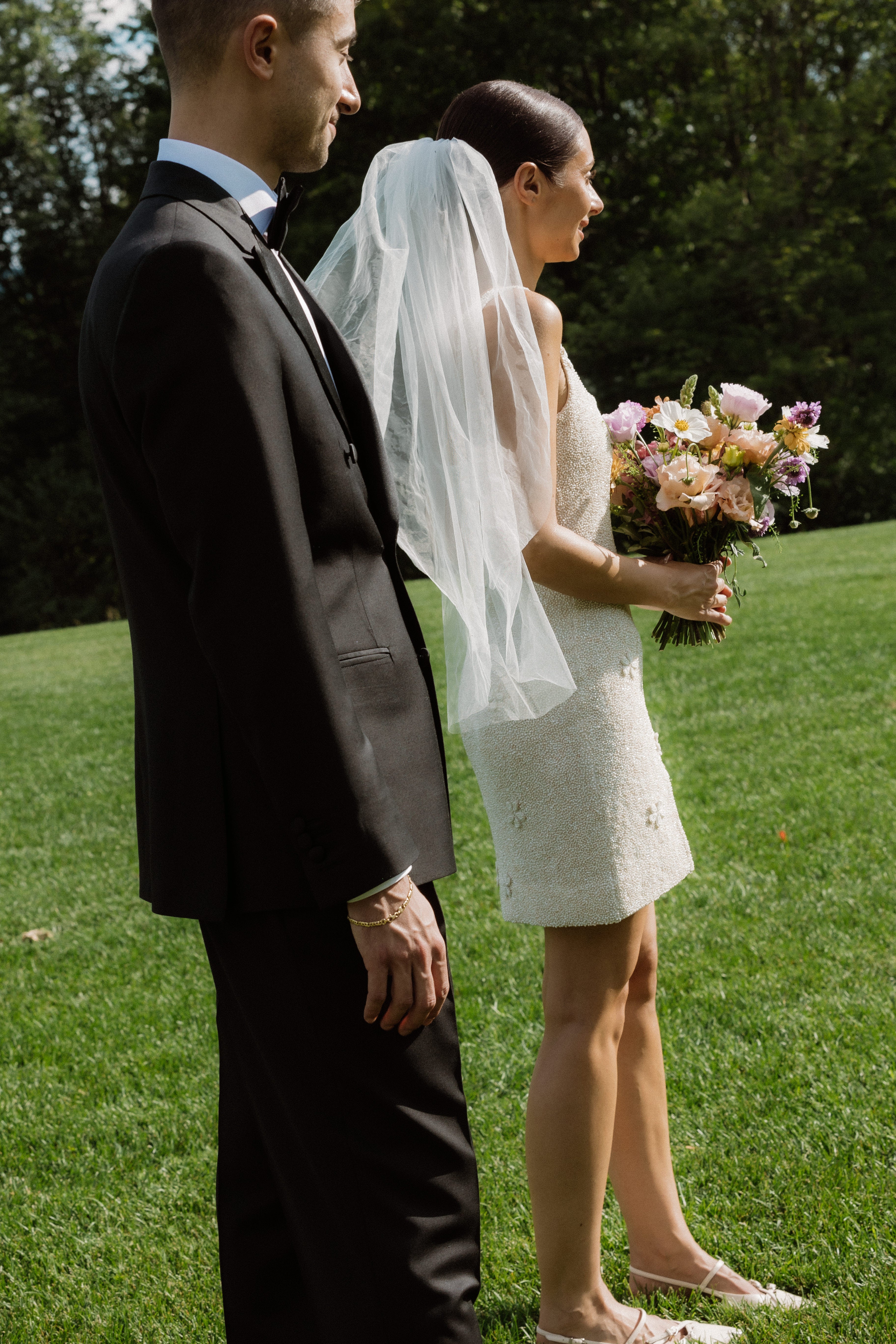 Man and woman in wedding attire standing on grass