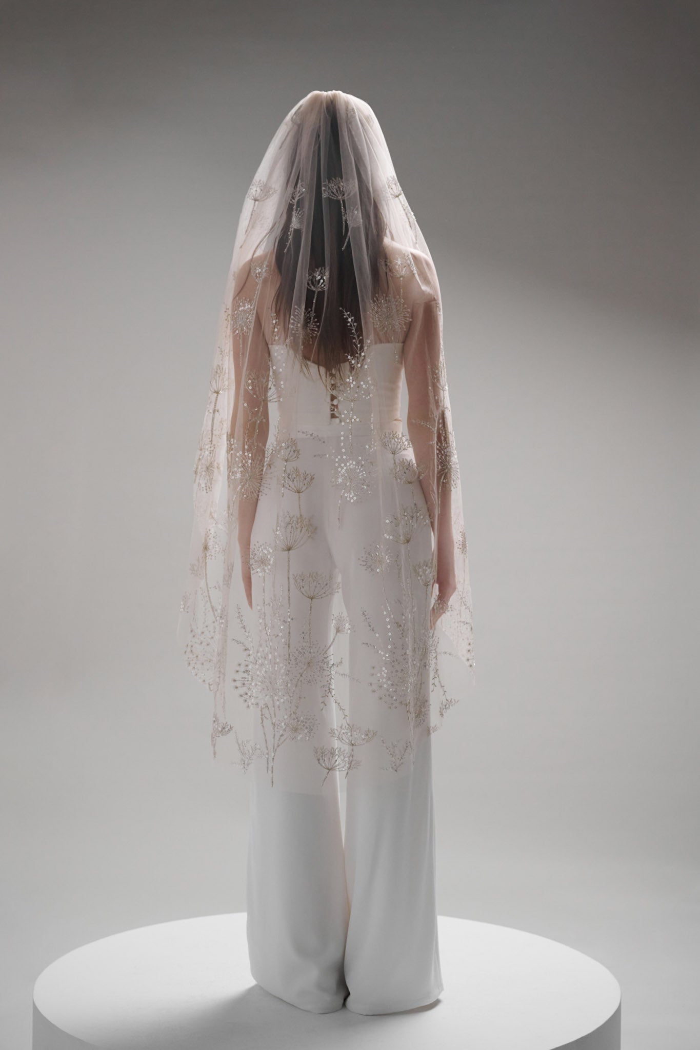 A champagne tulle veil, beaded and sequinned with ethereal dandelions and windswept reeds